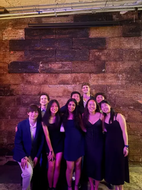 A smaller group in formal wear against a brick wall
