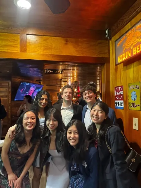Members posed together in a wood-paneled restaurant